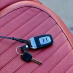 Set autosleutels met afstandsbediening op geribbelde rode leren autostoel