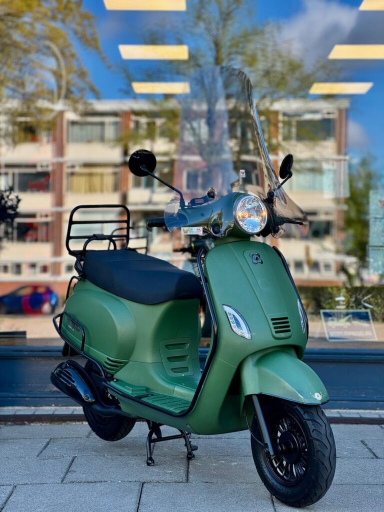 Matgroene retro-scooter met windscherm op standaard, voor een raam met weerspiegelde flats.