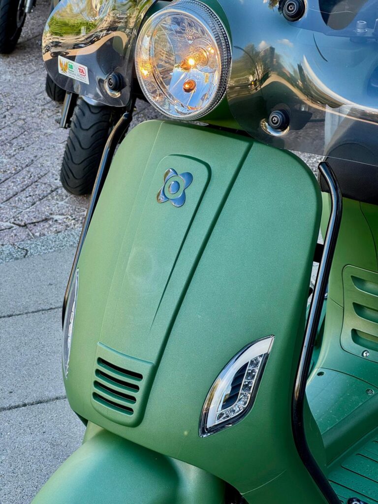 Detail van matgroene scooter met koplamp, knipperlichten en windscherm