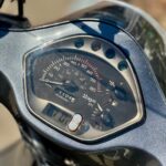 Close-up van het instrumentenpaneel van een scooter met snelheidsmeter, brandstof- en temperatuurmeter.