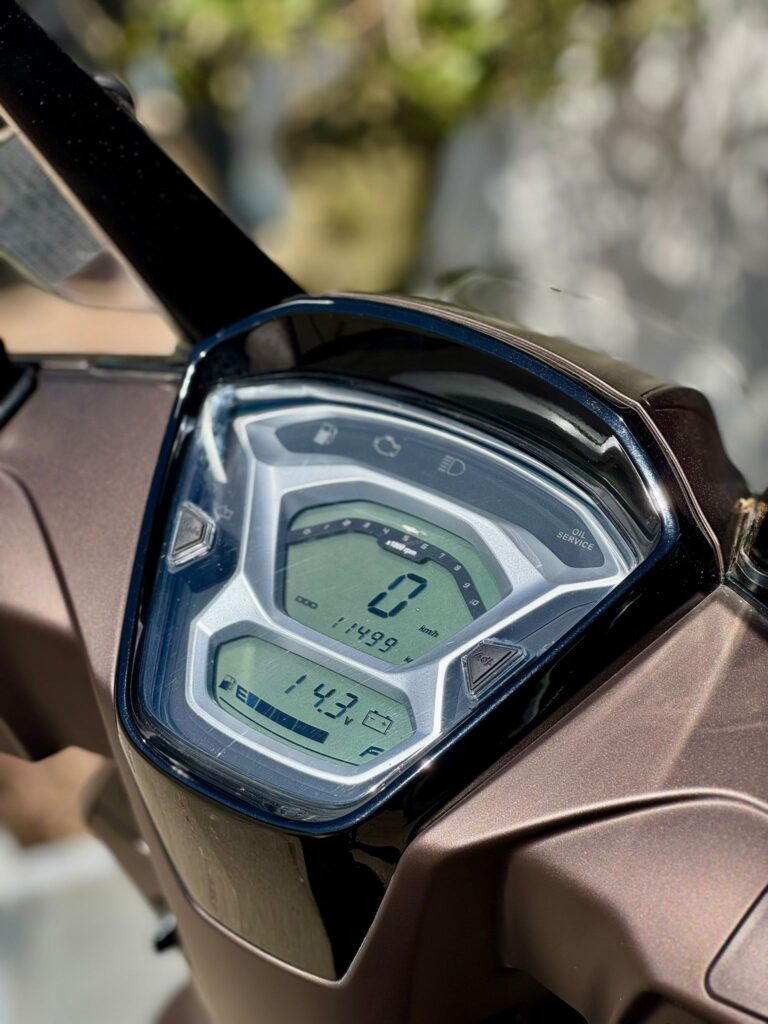 Close-up van het digitale dashboard van een scooter, met snelheidsmeter, odometer en brandstofniveau.