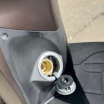 Open benzinedop van een scooter, vulopening zichtbaar naast de voetplaat.