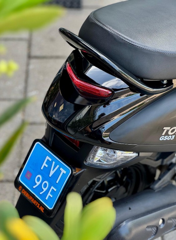 Close-up van de achterkant van een zwarte scooter met blauw kenteken en rood achterlicht.