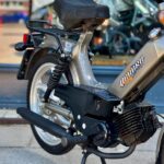 Close-up van een klassieke brommer met Quadro-logo, op standaard geparkeerd op de stoep.