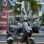 Zwarte elektrische scooter met hoog windscherm voor etalage van Kymco-dealer.