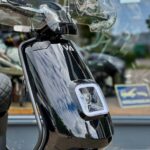 Close-up van de voorkant van een glanzend zwarte scooter met ruit en vierkante LED-koplamp.