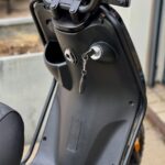 Close-up van een elektrische scooter met sleutel in het contact en een digitaal display.