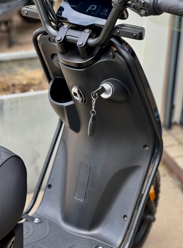 Close-up van een elektrische scooter met sleutel in het contact en een digitaal display.