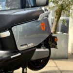 Close-up van de zijkant van een grijze Yadea E8S elektrische scooter op de middenstandaard, geparkeerd buiten.