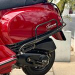 Close-up van de rode GTS-scooter: achterzijde met wiel, uitlaat en Toscana Dynamic-logo.