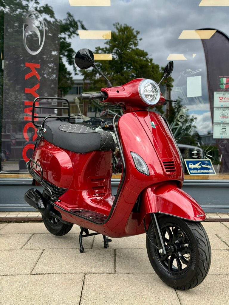 Glanzend rode scooter op de stoep, geparkeerd voor een winkel met grote ramen.