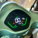 Digitaal dashboard van een elektrische scooter met snelheidsmeter en groene LED-indicatoren.