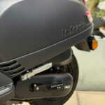 Close-up van de matte zwarte scooter, met voetsteun, wiel en La Souris-logo.