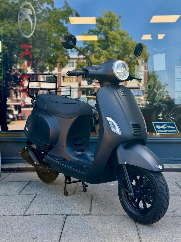 Matte zwarte scooter geparkeerd op de stoep voor een winkel met glazen pui