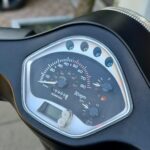 Close-up van het scooterdashboard met snelheidsmeter, brandstof- en temperatuurmeter.