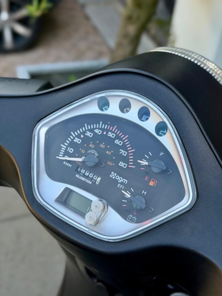 Close-up van het scooterdashboard met snelheidsmeter, brandstof- en temperatuurmeter.