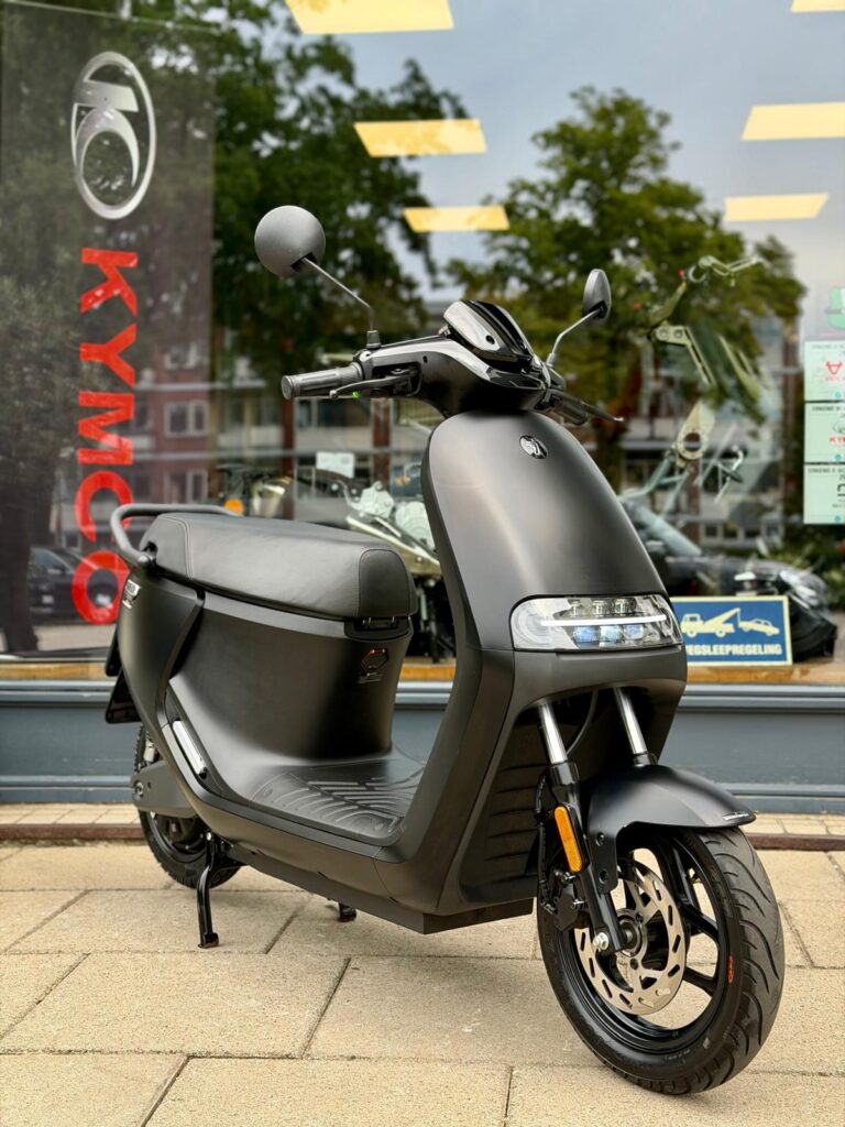 Matzwarte scooter op standaard met LED-koplamp en schijfrem, voor een winkelruit.