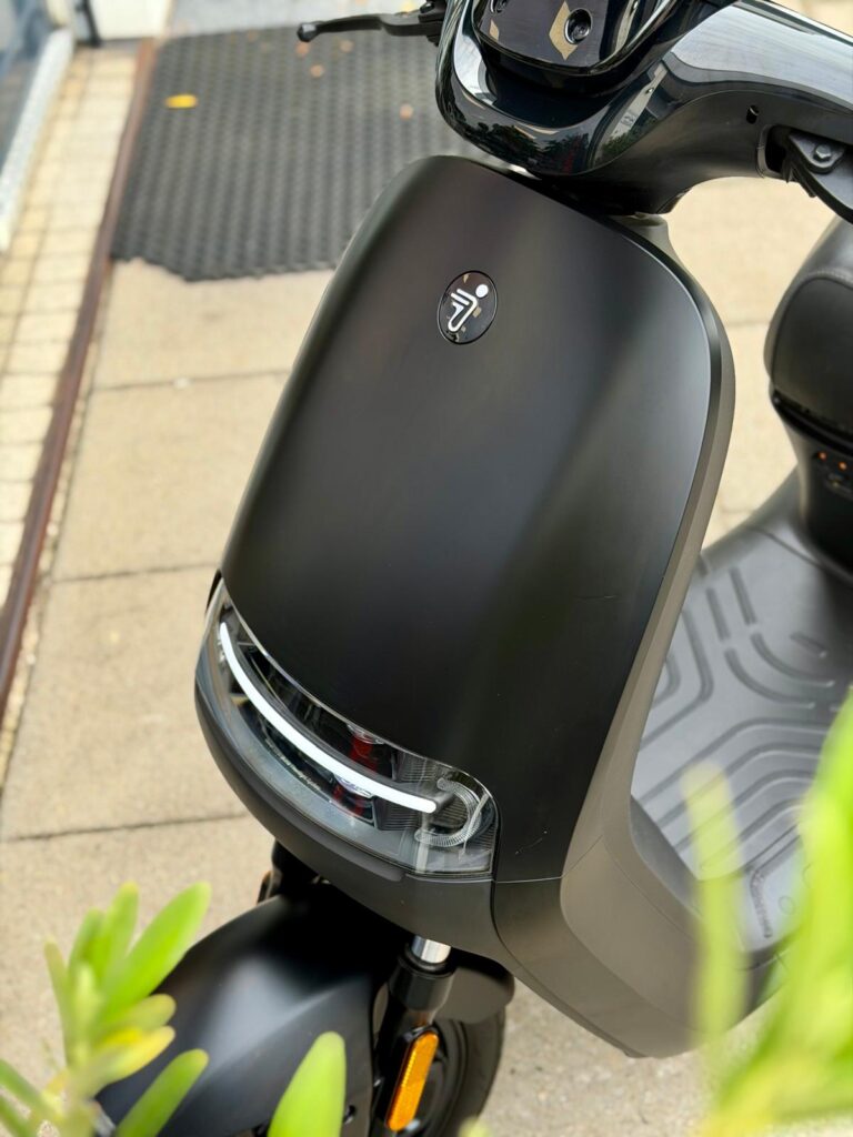 Close-up van de voorkant van een matzwarte elektrische scooter met LED-koplamp.