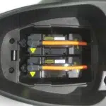 Twee uitneembare accu's met oranje hoogspanningskabels in het batterijvak van een elektrische scooter.