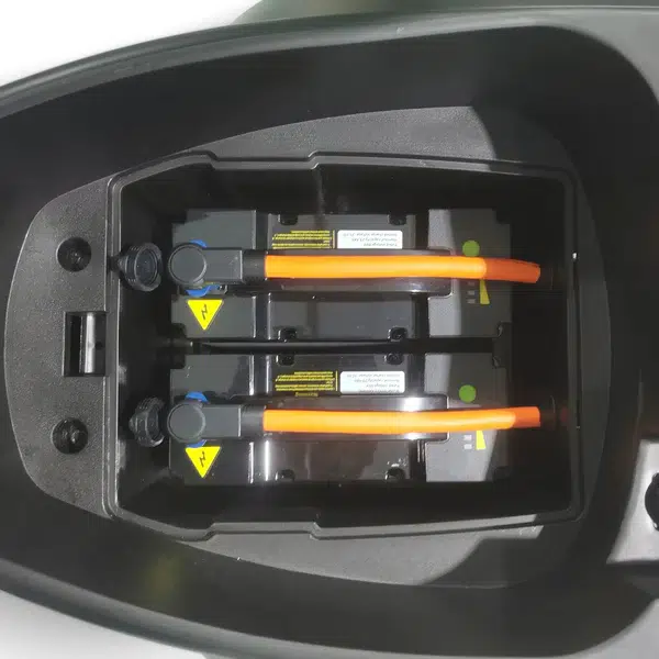 Twee uitneembare accu's met oranje hoogspanningskabels in het batterijvak van een elektrische scooter.