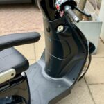Close-up van het stuur, dashboard en voetplaat van een zwarte scooter op straat.