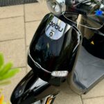 Close-up van een glanzende zwarte elektrische scooter met windscherm en ledknipperlichten