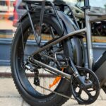 Close-up van het achterwiel en aandrijving van een fatbike e-bike met bagagedrager en spatbord.