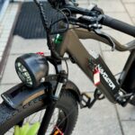 Close-up van een zwarte elektrische fatbike met dikke banden, koplamp en display op het stuur.