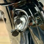 Close-up van een scooterslot met sleutel in het contact van een glanzende zwarte scooter.