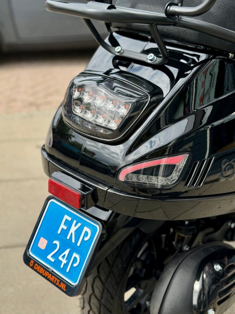 Achterkant van een zwarte scooter met LED-achterlicht, reflector en blauwe NL-kentekenplaat.