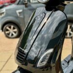 Close-up van de glanzende zwarte scooter met koplamp en led-knipperlichten buiten geparkeerd.