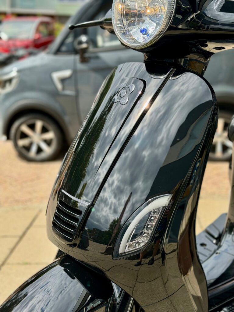 Close-up van de glanzende zwarte scooter met koplamp en led-knipperlichten buiten geparkeerd.