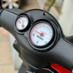 Close-up van het dashboard van een scooter met snelheidsmeter en brandstofmeter.