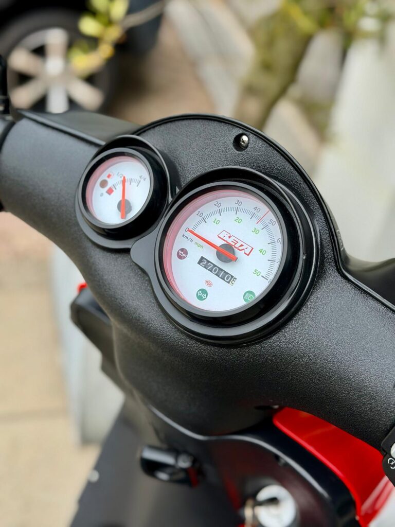 Close-up van het dashboard van een scooter met snelheidsmeter en brandstofmeter.
