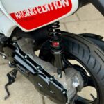 Close-up van het achterwiel en de schokdemper van een scooter met rode 'Racing Edition' sticker.