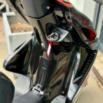 Close-up van een zwarte scooter met contactsleutel en rood sleutelhangerlabel.
